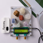 A Bexxly Harmonia Sequence Pro crystal resonance analyzer kit shown on a white background, featuring a clear square circuit board with various colored crystals, a green LCD screen, a white Bexxly device, and its green and white manual.