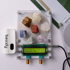 A Bexxly Harmonia Sequence Pro crystal resonance analyzer kit shown on a white background, featuring a clear square circuit board with various colored crystals, a green LCD screen, a white Bexxly device, and its green and white manual.
